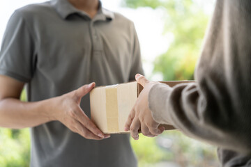 Happy smiling woman receives boxes parcel from courier in front house. Delivery man send deliver...