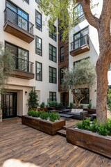 Fototapeta premium A modern courtyard design with white apartment buildings, a patio furnished with seating, and planters of greenery.