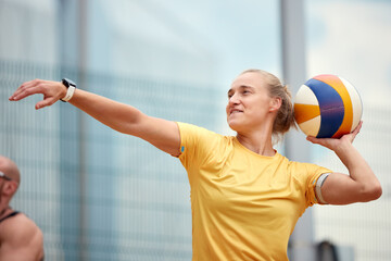 Woman in activewear throwing a volleyball during an outdoor team game