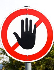 Red circular sign with a black hand and diagonal red bar, prohibiting contact