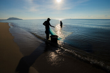 Silhouette of Fishermen on the beach in the evening.