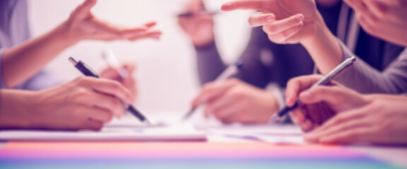 People are collaborating at a table with pens and paper in a meeting, expressing teamwork, creativity, and shared ideas in a collaborative office environment with focus and productivity.