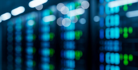 Blurred server racks in a data center with blue and green lights glowing softly, creating a futuristic atmosphere that suggests technology, energy, and digital infrastructure.