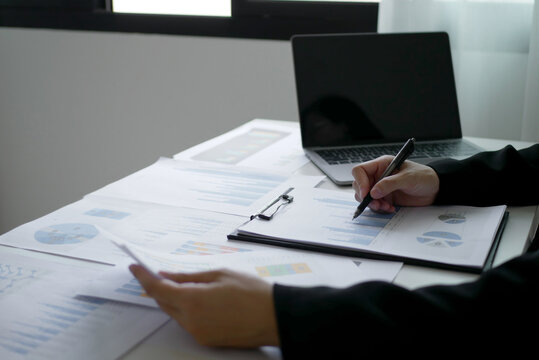 Businesswoman sitting at the table holding a pen, calculating graphs and planning the process of successful business growth