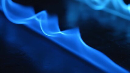 Captivating close-up footage of mesmerizing blue flame dance against a dark background