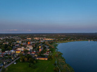 Fototapeta premium Aerial view of Võru, Estonia at sunset, featuring the serene Tamula Lake and surrounding townscape. Perfect for nature, travel, or cityscape themes with peaceful, scenic countryside vibes.