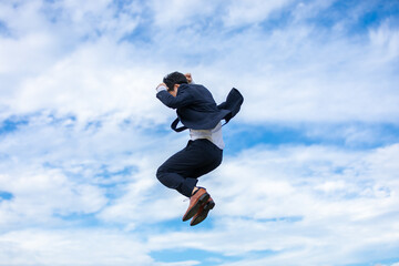 青空にジャンプするビジネスマン