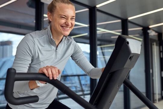 Smiling woman exercising on an elliptical trainer in a modern fitness center