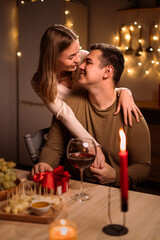 Valentine's Day concept. Celebrating Valentines Day at home. Young couple in love hug while have romantic dinner.