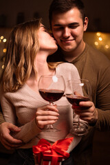 Young Couple in love with wine glasses celebrating Valentine's day in the evening at home, kissing and hugging. Romantic and love.