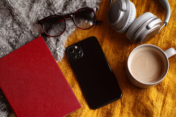 A phone, a cup of coffee, and a pair of sunglasses are on a table
