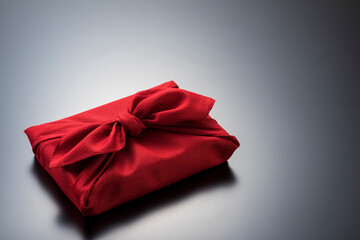 黒色の背景に風呂敷に包まれた手土産