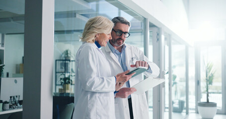 Teamwork, tablet and planning with doctors in hospital for healthcare report, research and reading. Medical case review, clinical guidelines and telehealth app with mature people for diagnosis