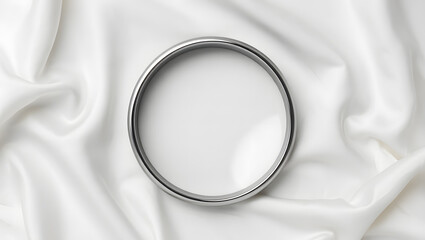 Elegant silver bangle bracelet on luxurious white fabric folds for high-end jewelry photography
