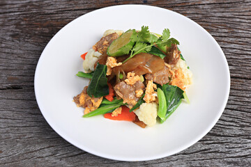 Stir-fried Rice Noodles with Soy Sauce and Pork (Pad See Ew) in white plate on old wooden screen