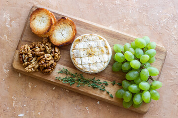 Baked brie cheese with grapes, thyme, baguette and nuts. French cuisine. Vegetarian food.