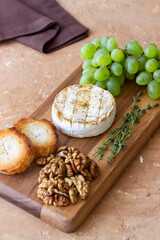 Baked brie cheese with grapes, thyme, baguette and nuts. French cuisine. Vegetarian food.