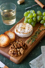 Baked brie cheese with grapes, thyme, baguette and nuts. French cuisine. Vegetarian food.