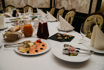 Various dishes and drinks stand on a table covered with a white tablecloth during a feast at a holiday