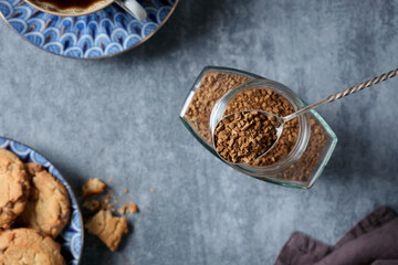 Top view a instant coffee in a spoon against the background of a glass jar, cup with coffee and...