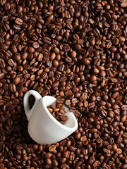 Top view of roasted coffee beans background, white cup espresso and spoon.