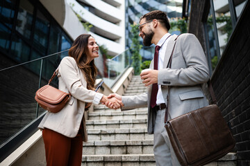 Businesspeople shaking hands on stairs in urban setting
