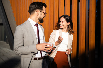 Business partners walking and talking during coffee break outside office building