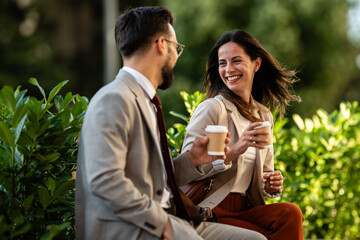 Business colleagues enjoying coffee break outdoors, smiling and talking