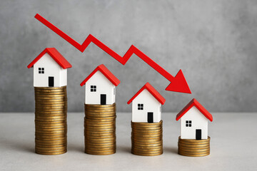 Miniature houses on stacks of gold coins with a red downward trending graph line home model