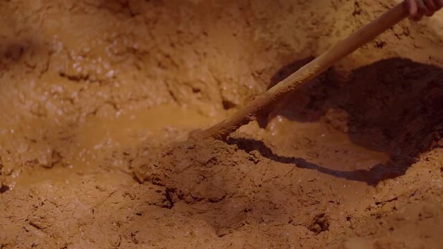 Construction worker blending mud and straw, creating adobe bricks using traditional sustainable method in rural Chapada dos Veadeiros landscape, Brazil, slow motion shot