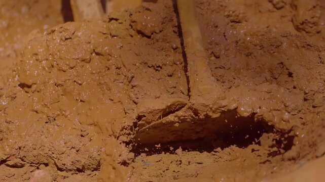 Construction worker from Kalunga community mixing earth with bare feet, creating adobe bricks using traditional bioconstruction technique in Chapada dos Veadeiros, Brazil, preserving cultural heritage