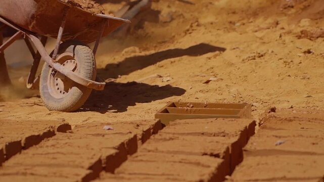 Construction worker creating adobe bricks with wheelbarrow and wooden mold in Chapada dos Veadeiros, highlighting traditional building methods and local craftsmanship in Brazil