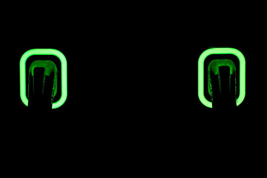 Two glowing green buttons illuminated in darkness, symbolizing technology, modern design, interface interaction, and futuristic control elements. - Powered by Adobe