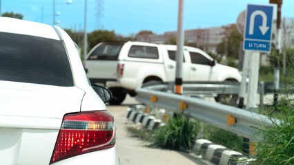 Rear side of white car with right turn signal. Open for u-turn on the road. Front of car the other...