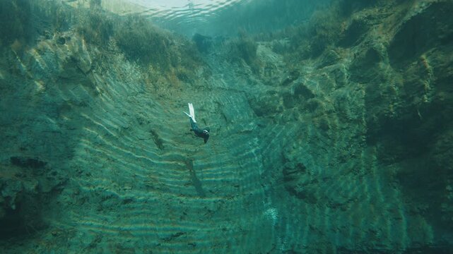 Freediver in the karst lake. Woman freediver swims underwater in the crystal clear lake named Goluboye Ozero near the city of Samara, Russia