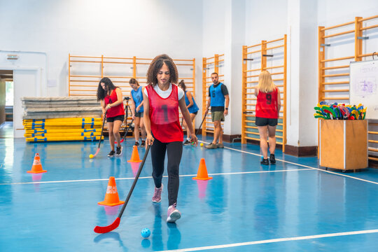 Female athlete dribbling ball during floor hockey training in gym - Powered by Adobe