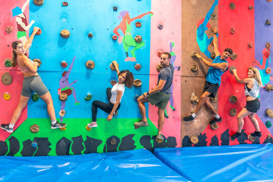 Group of athletes climbing a colorful indoor climbing wall