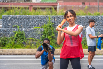 Female baseball player holding bat ready to hit ball during game