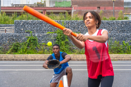 Female baseball player batting and male catcher waiting for the ball