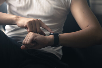 Young Asian man in sportswear checking her workout results on a smart watch while resting at the...