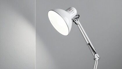 Modern white desk lamp with metallic adjustable arm, turned on against a light gray wall