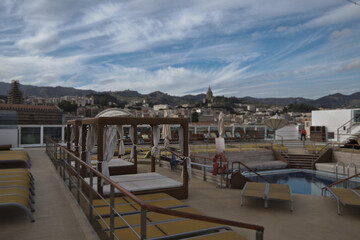 Pooldeck or swimmingpool with sun deck on modern cruiseship or cruise ship liner with elegant lounge furniture deck chairs and rattan sun beds loungers