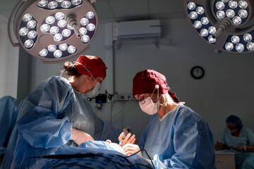 Surgeons performing precise operation under bright surgical lights