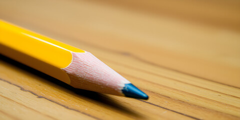 Obraz premium This close-up photo showcases a vibrant yellow pencil placed on a wooden table. The pencil appears sharp and ready for use, with intricate details visible up close.
