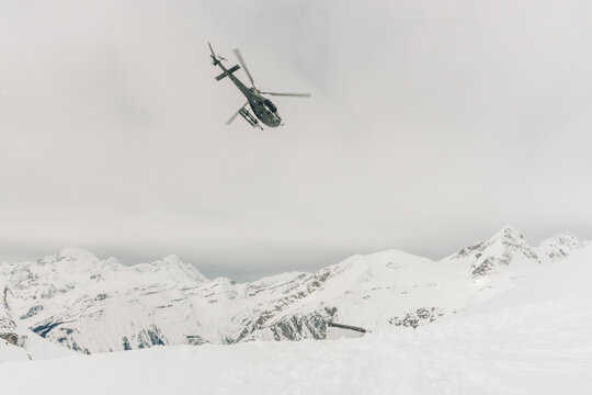 A helicopter takes off from a winter snow landing.