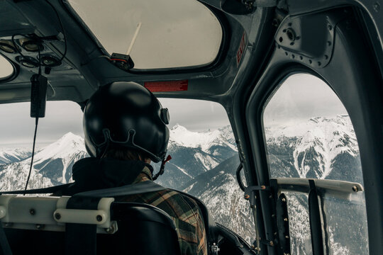 A helicopter pilot flies in the mountains.