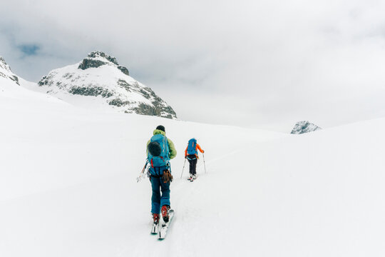 Two skiers skin up a hill in the backcountry.