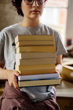 Closeup stack of books in hands of a teenage girl at book shop