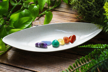Aura. Different natural mineral stones and green leaves on wooden table, closeup