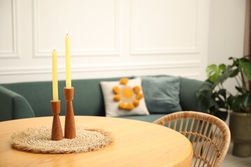 Wooden table with candles and stylish chair in dining room, closeup